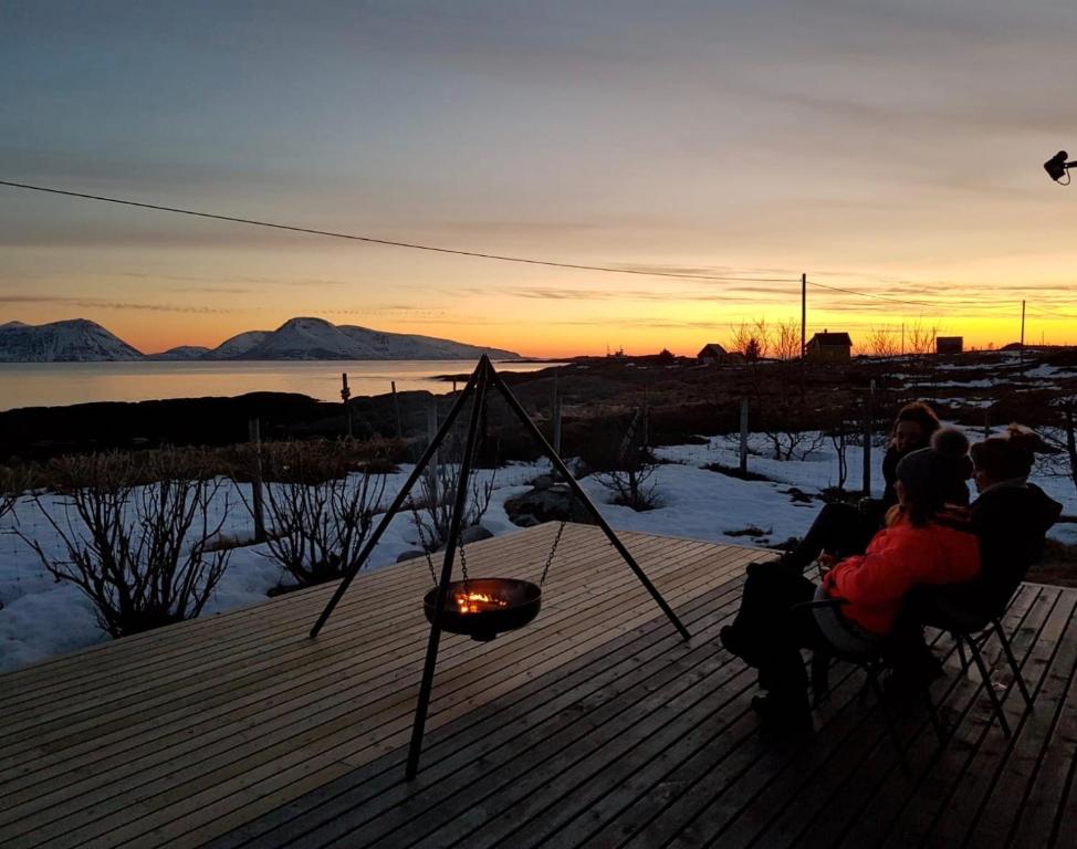 a group of people sitting on a deck watching the sunset at Aurora exotic cabin in Vannareid