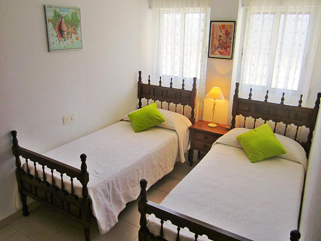 1 dormitorio con 2 camas y almohadas verdes en Playa Dorada B106, en Cambrils