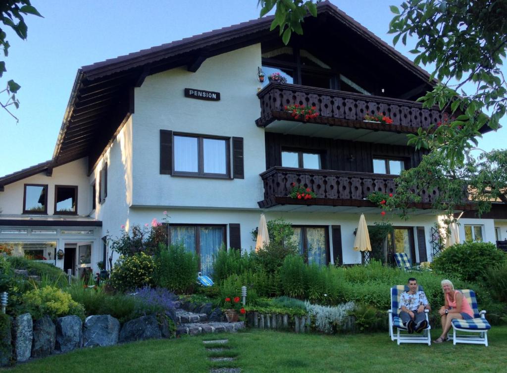 two people sitting in chairs in front of a house at Landhaus Florian in Winterberg