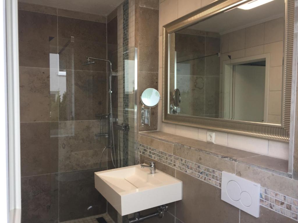 a bathroom with a sink and a shower and a mirror at Neues Zimmerapartment mit Bad in Neckarwestheim