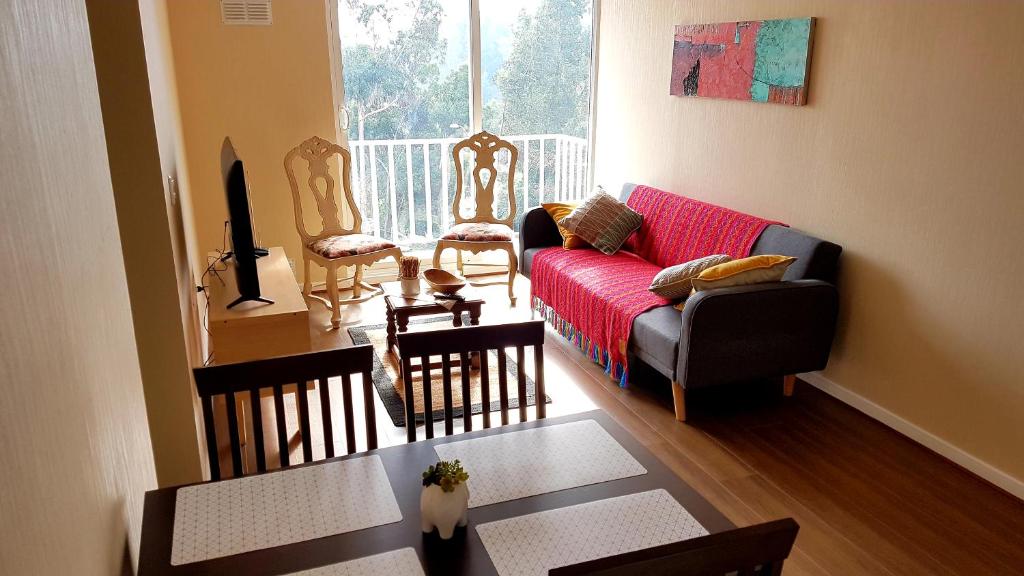 a living room with a red couch and two chairs at Departamento nuevo full equipado in Valdivia