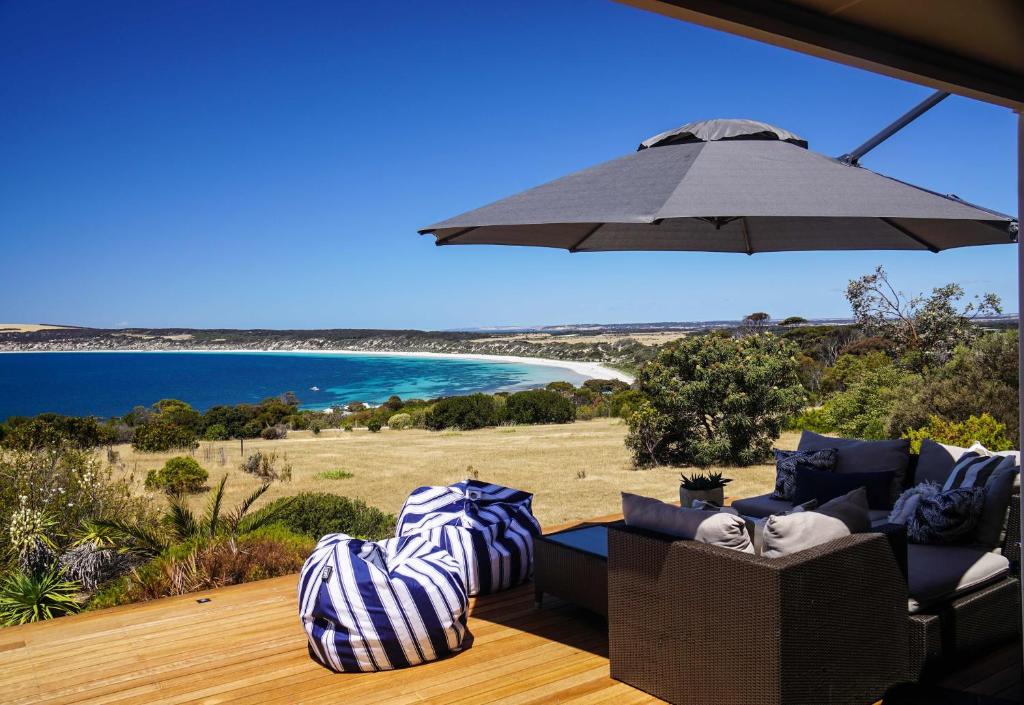 a patio with chairs and an umbrella and the ocean at The Cape in Emu Bay