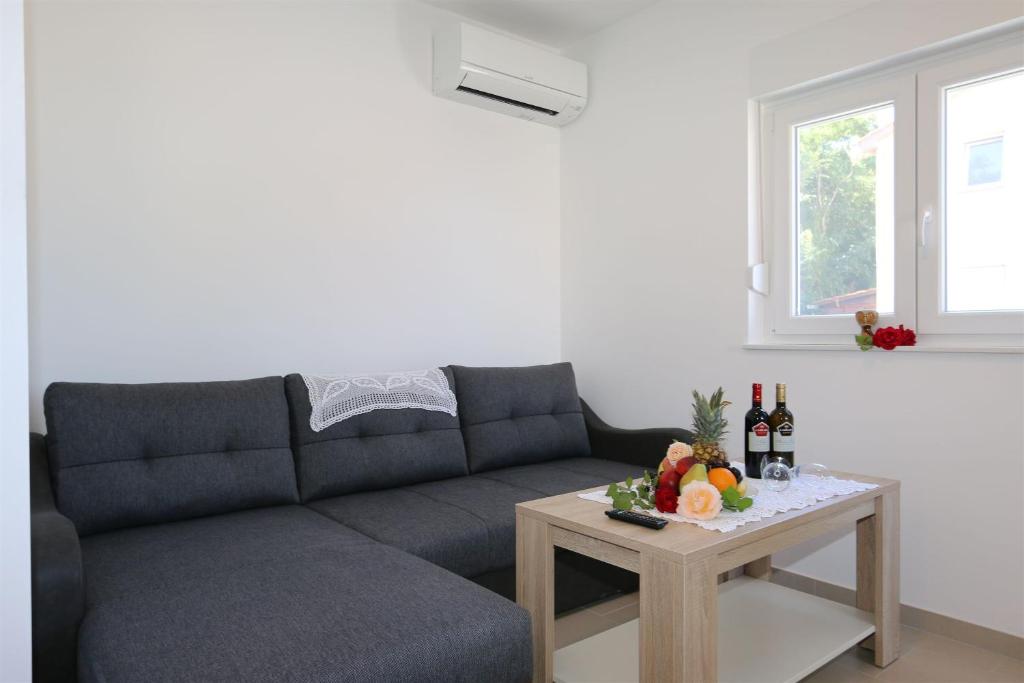 索林納的住宿－Apartments Maric-Hlapa，客厅配有沙发和一张桌子,桌子上摆放着水果和葡萄酒瓶