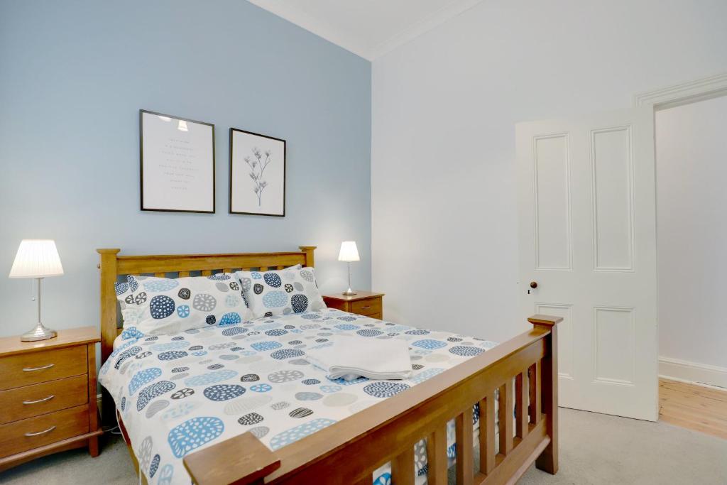 a bedroom with a bed with a wooden bed frame at Bath Street Cottages in Adelaide