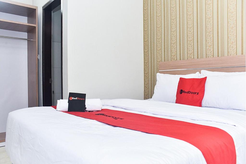 1 dormitorio con 1 cama grande con almohadas rojas y blancas en RedDoorz Plus near Malang Town Square, en Malang