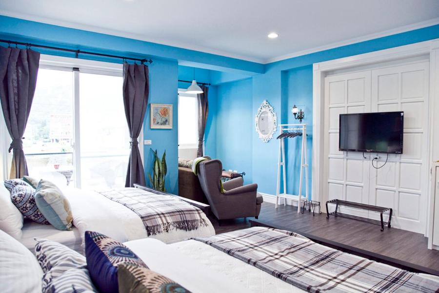a blue bedroom with two beds and a chair at Antlers Guest House in Taitung City