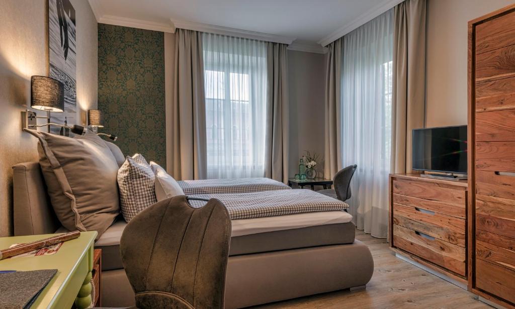 Schlafzimmer mit einem Bett, einem TV und einem Schreibtisch in der Unterkunft Hotel Starnberger See in Starnberg