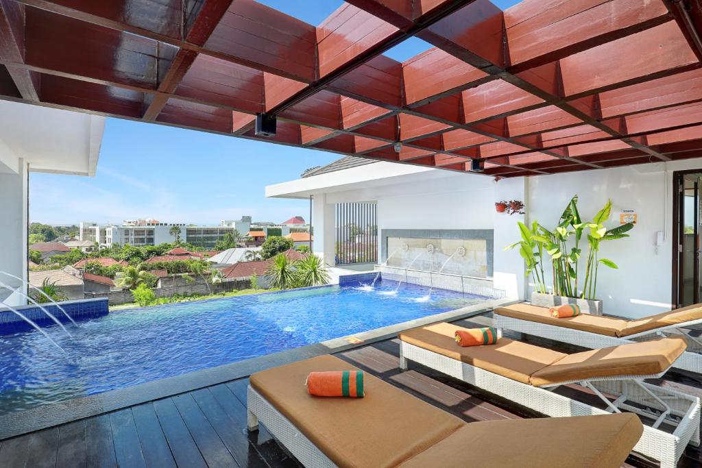 una piscina en una sala de estar con sillas y una piscina en HARRIS Hotel Seminyak, en Seminyak