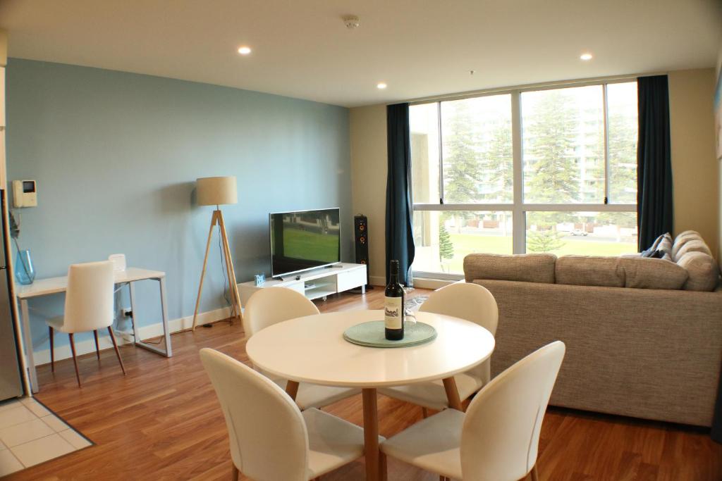 uma sala de estar com uma mesa e cadeiras e um sofá em Beachside Luxury Apartments One & Two Bedroom in Beachfront Oaks Pier Building em Glenelg