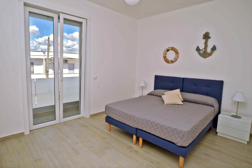 een slaapkamer met een blauw bed en een groot raam bij Altomare Case Vacanza in Porto Cesareo