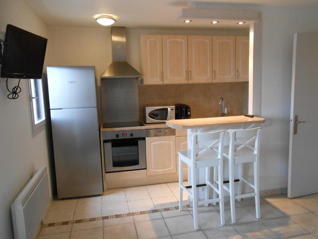 La cuisine est équipée d'un réfrigérateur et d'un comptoir avec tabourets. dans l'établissement Anglet/Biarritz 300m des plages - Proximité Golf & Phare - 1/4 pers. - Parking privé, à Anglet