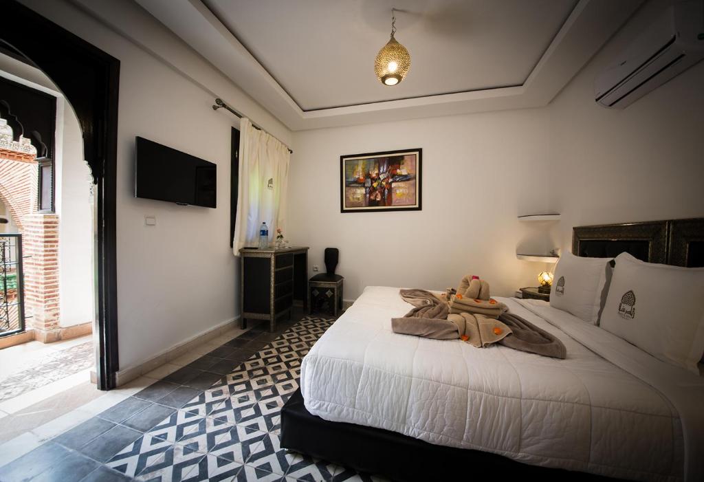 a bedroom with a large white bed with a teddy bear on it at Riad Challa Hotel & Spa in Marrakesh