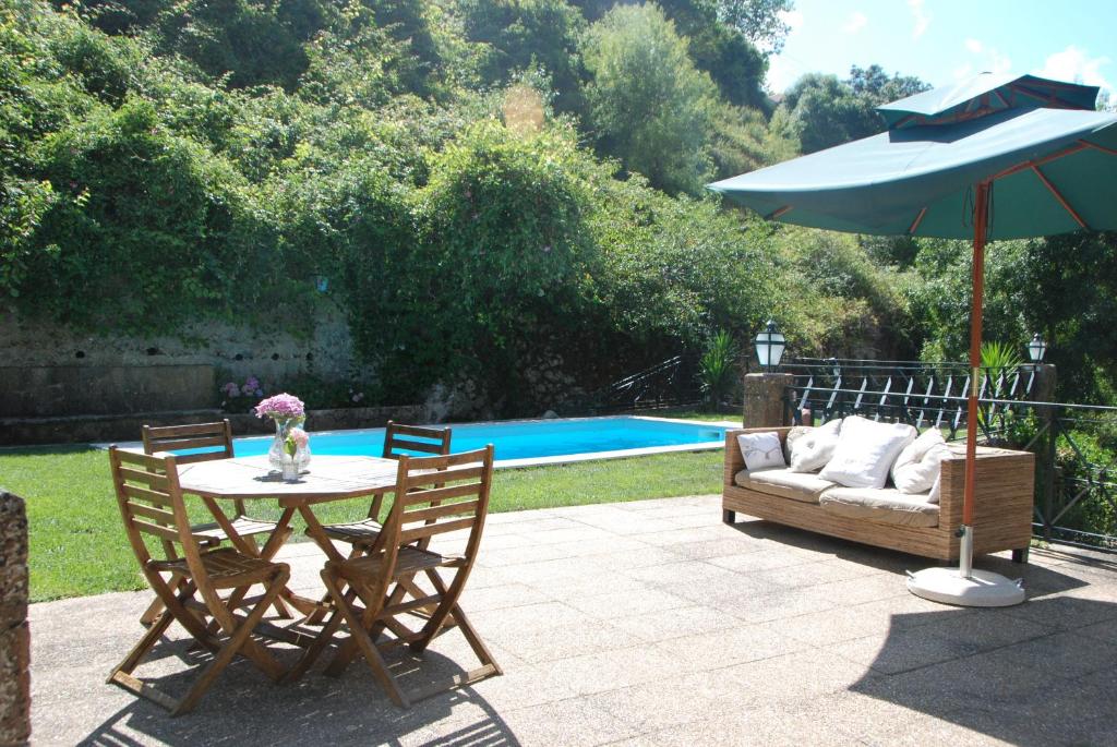 a patio with a table and a couch and an umbrella at Sintra Center Guest House Escape to Nature in Sintra