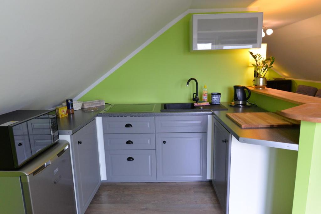 a kitchen with white cabinets and a green wall at Apartament u Robsona in Wilkasy