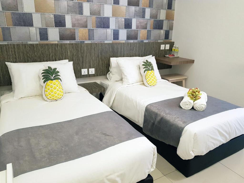 two beds in a hotel room with pineapple pillows at Tas 96 Inn in Kuantan