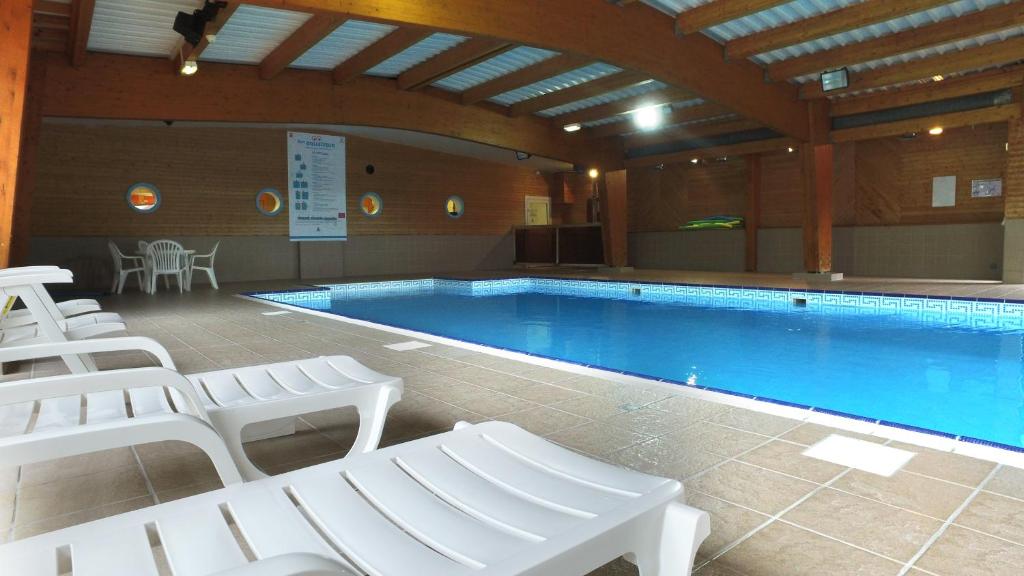 a large swimming pool with white chairs around it at VVF Le Lioran Les Monts du Cantal in Saint-Jacques-des-Blats