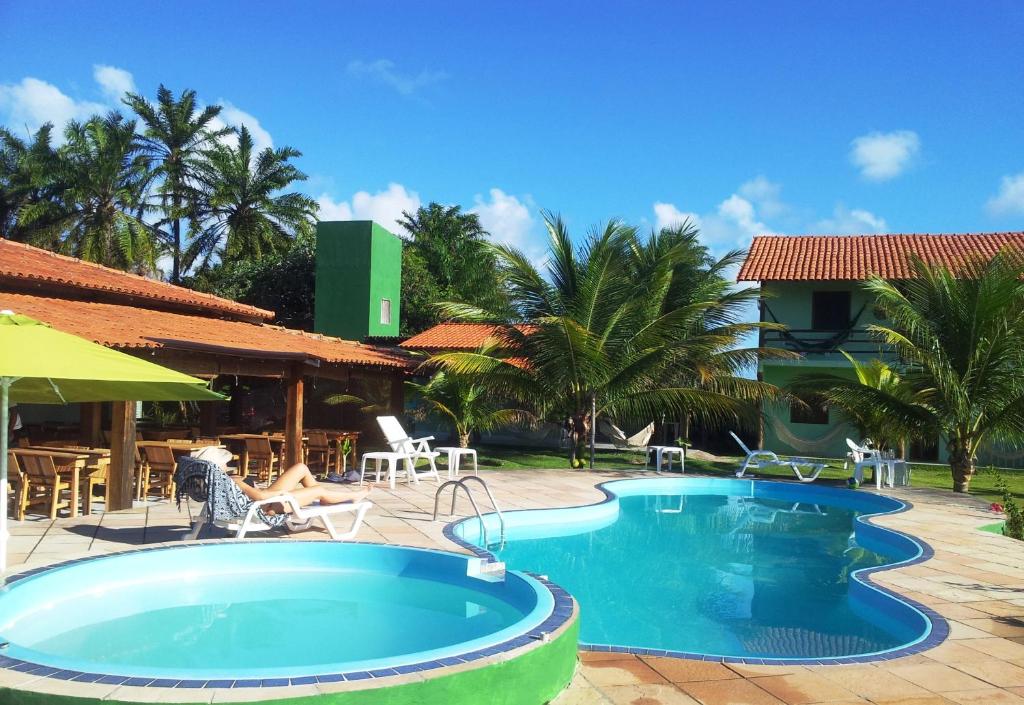 una piscina en un complejo con palmeras en Sol da Onda Pousada e Flats, en Barra Grande