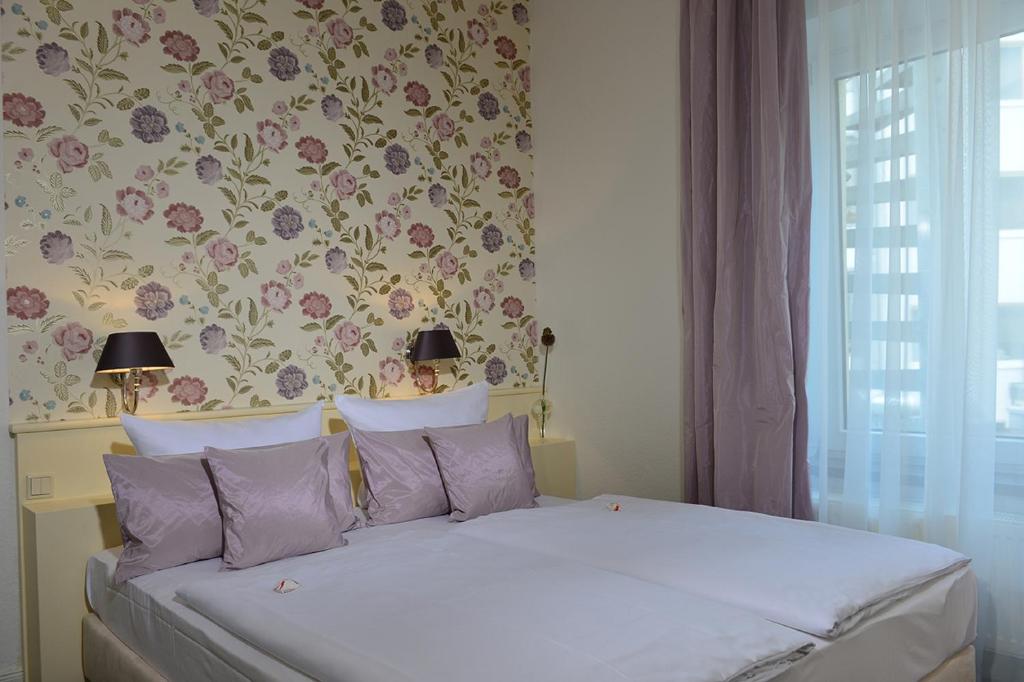 1 dormitorio con 1 cama y papel pintado con motivos florales en Hotel Domspitzen en Colonia