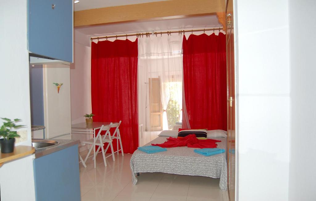 マドリードにあるEstudio Las Huertasの赤いカーテン付きのベッド、キッチンが備わる客室です。