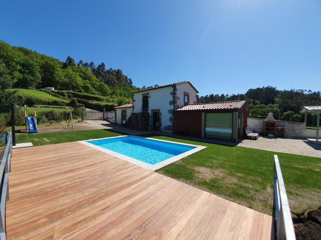 a backyard with a swimming pool and a wooden deck at Quintinha de Labrujó in Ponte de Lima