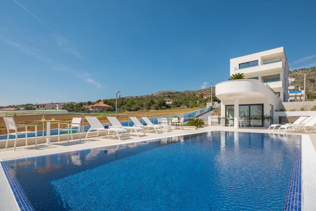 Una piscina con sillas y un edificio. en Luxury Apartments Baotić, en Trogir