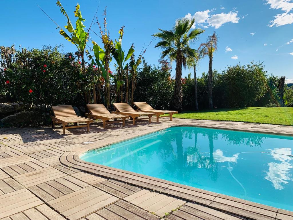a swimming pool with benches and trees and a yard at Villa Angel in La Gaude