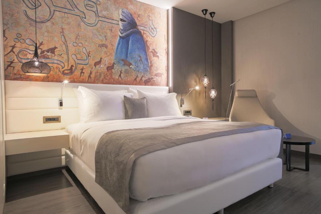 a bedroom with a large bed with a painting on the wall at The Legacy Luxury Hotel, Algiers in Alger