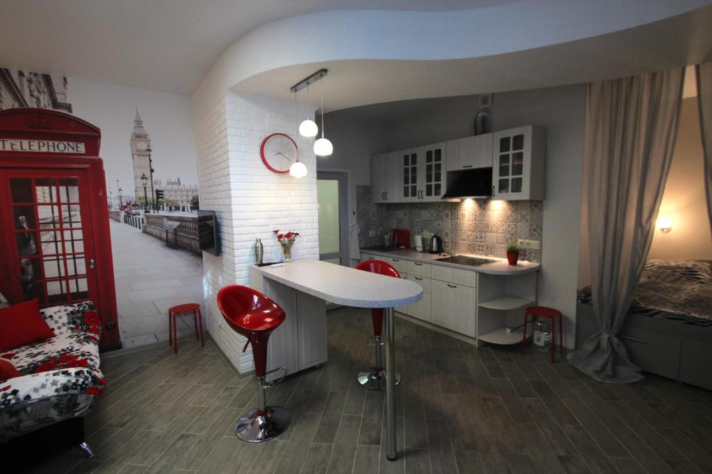 a kitchen and living room with red chairs and a counter at Уютная Студия на Парковой 29 in Sevastopol