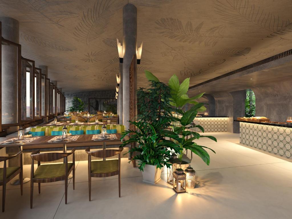 a restaurant with a table and chairs and a plant at Cinnamon Bentota Beach - Signature Selection in Bentota