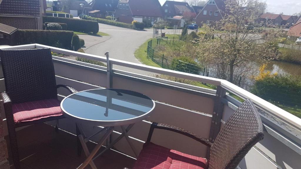 a table and chairs on a balcony with a view of a river at 50040 FeWo kleine Nordseeliebe in Altfunnixsiel