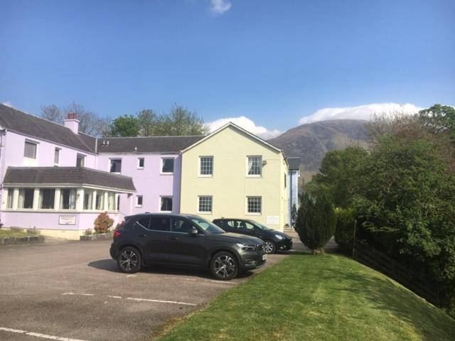 dos autos estacionados en un estacionamiento frente a una casa en Fort William Studios en Fort William