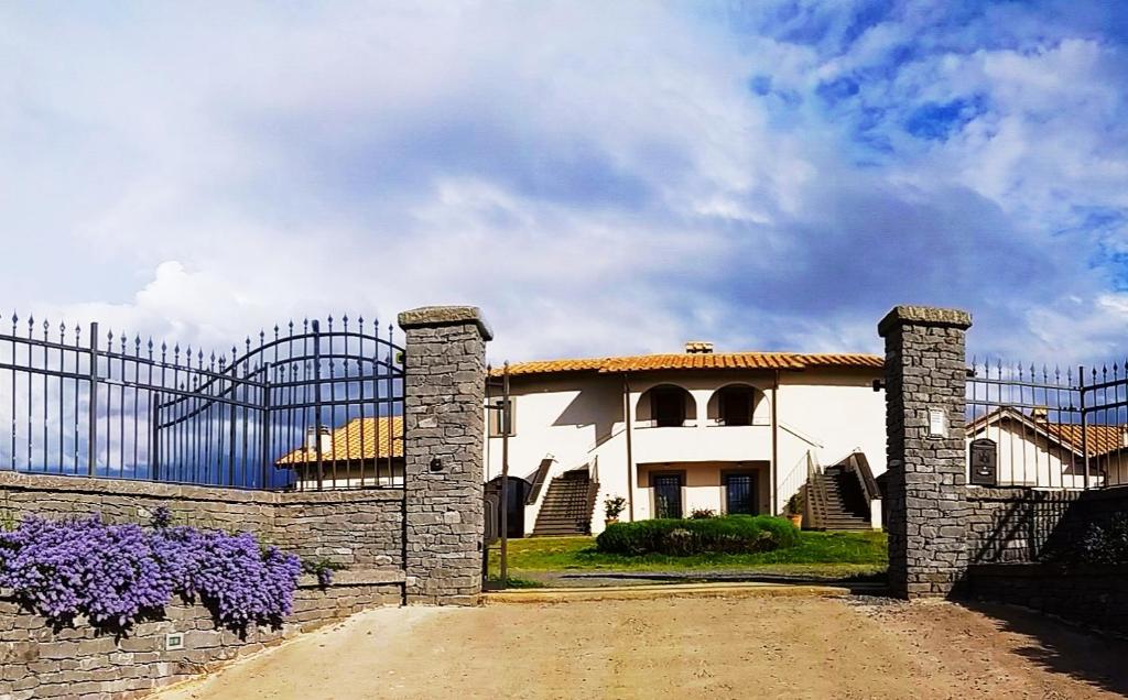 una casa blanca con una valla y flores púrpuras en Agriturismo PIAN DEL GRANO Azienda agricola, en Grotte di Castro