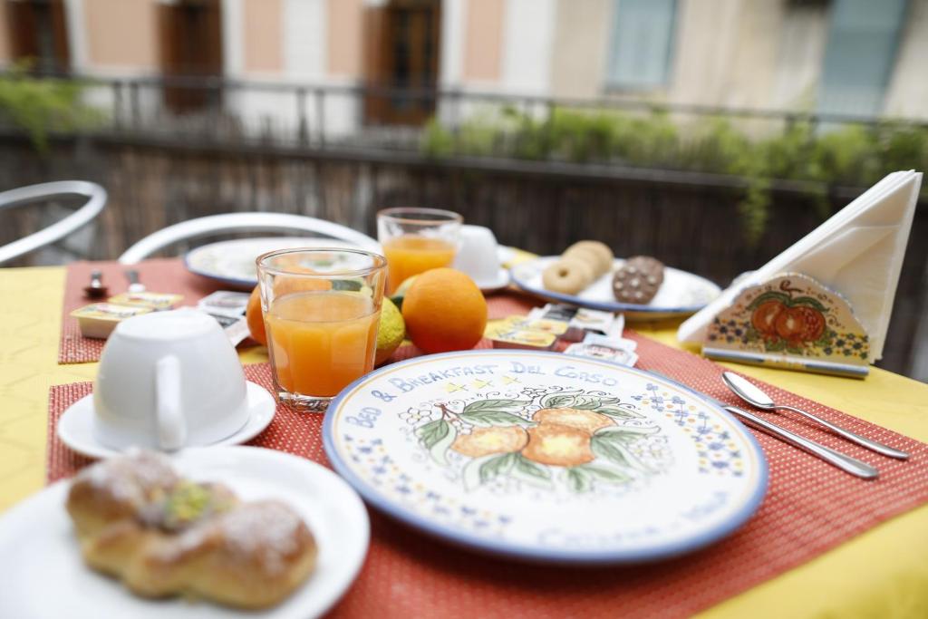 una mesa con platos de comida y vasos de zumo de naranja en B&B Del Corso en Catania
