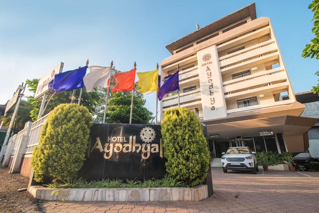 una señal frente a un edificio con banderas en Hotel Ayodhya, en Kolhapur