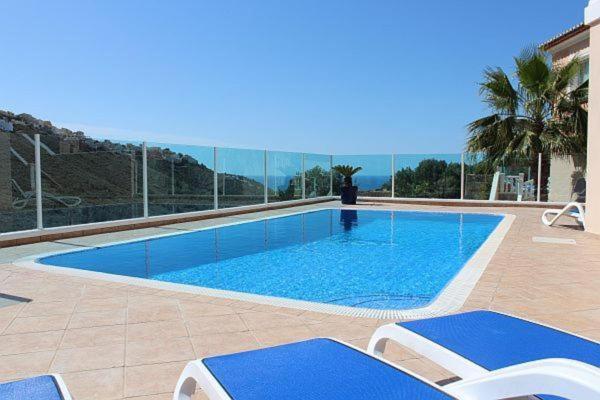 a swimming pool with chairs and the ocean in the background at Villa Guapa With Gym Aircon Wifi Moraira in Moraira