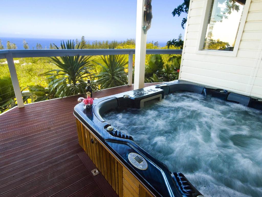 bañera de hidromasaje en la cubierta de una casa en White House Ocean View Spa Villa, en Burnt Pine