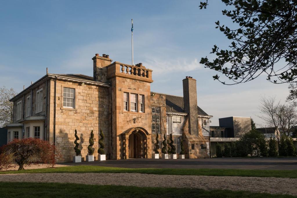 an old brick building with a flag on top at Dalmeny Park House Hotel in Barrhead