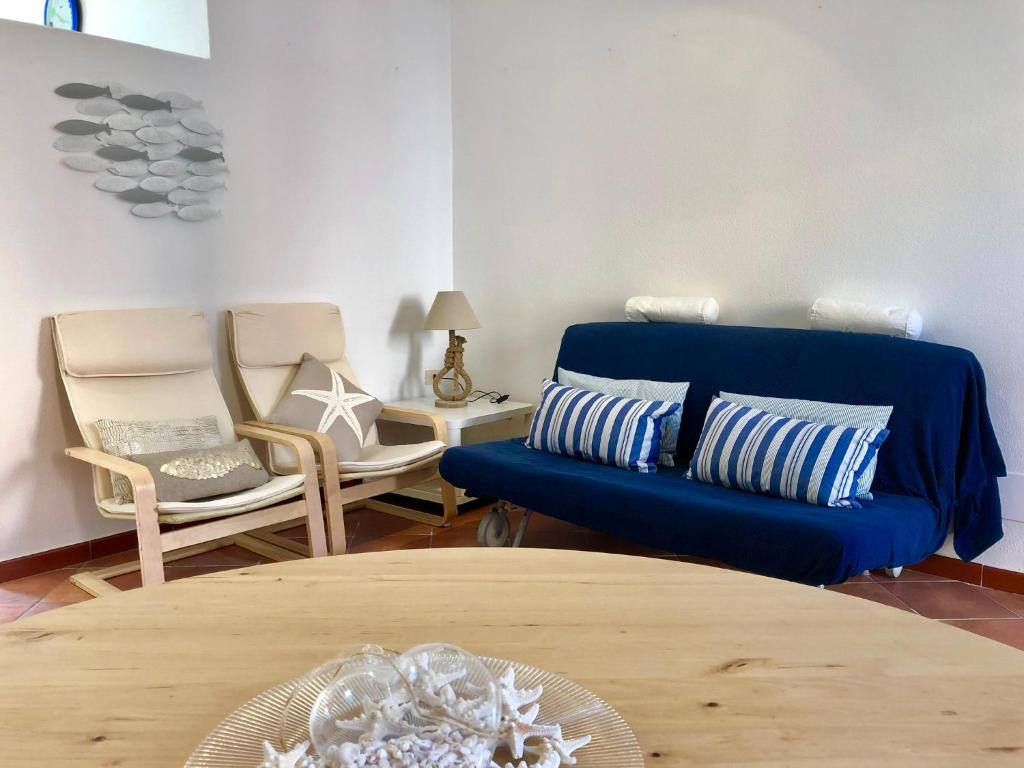 sala de estar con sofá azul y sillas en Il Gabbiano en Santa Teresa Gallura