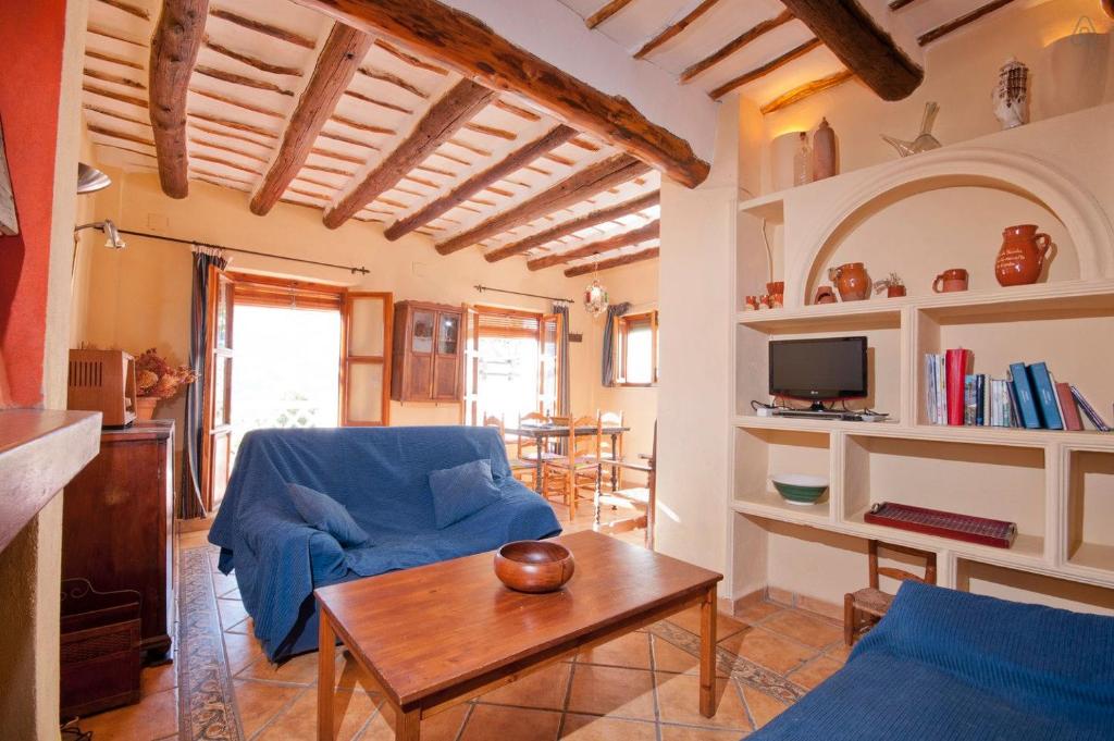 a living room with a blue couch and a table at Casa de la Luz in Bubión