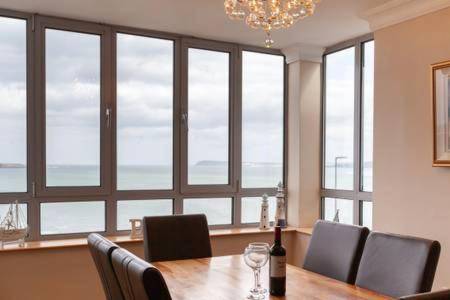 a dining room with a table and chairs and windows at Blue Pool View in Portrush