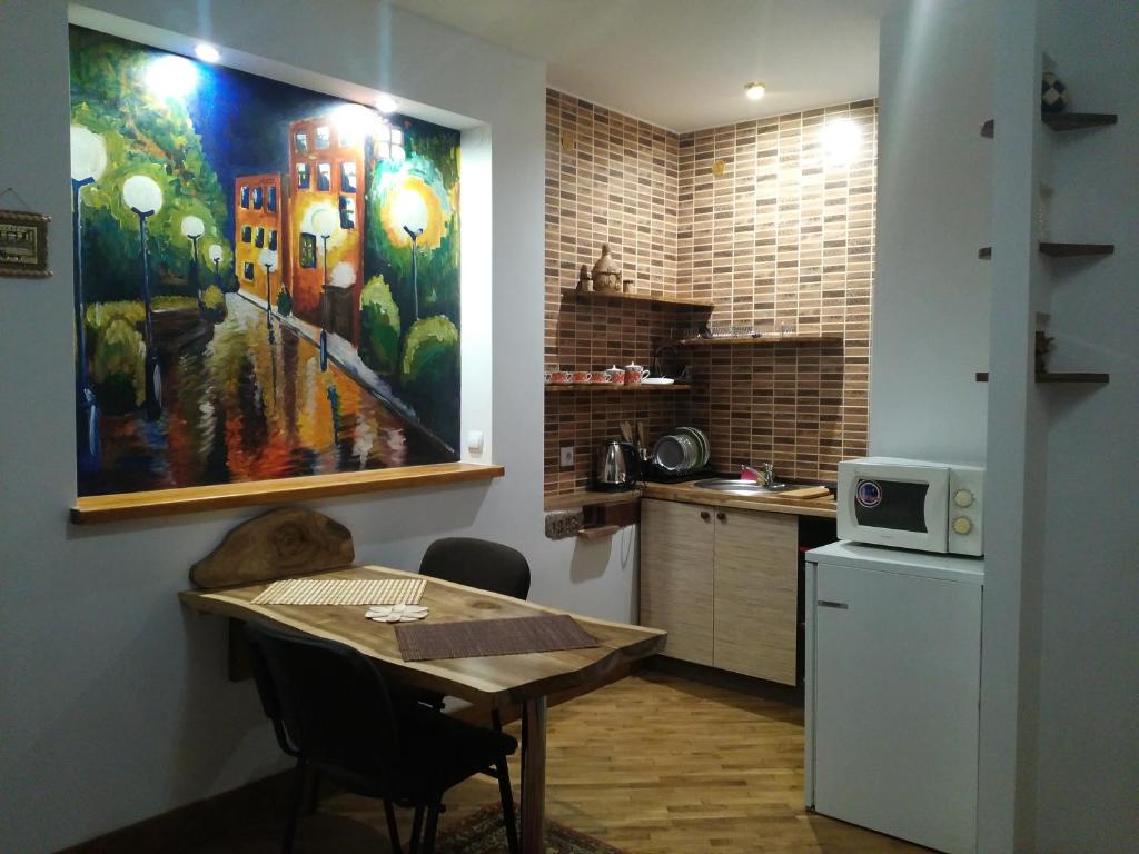 uma cozinha com uma mesa e um quadro na parede em Квартира-студія Шале em Truskavets