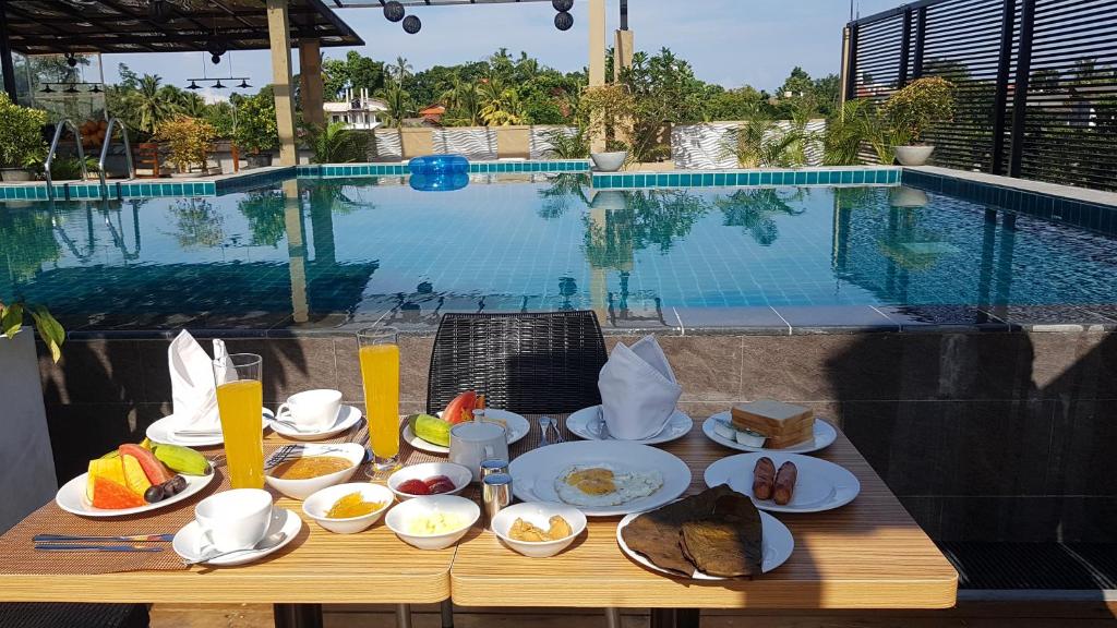 a table with plates of food next to a swimming pool at Pinnacle boutique villas in Galle