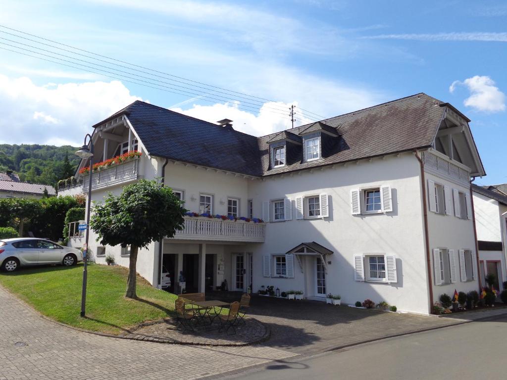 um grande edifício branco com uma árvore em frente em 19 Im Herrenfeld em Burgen