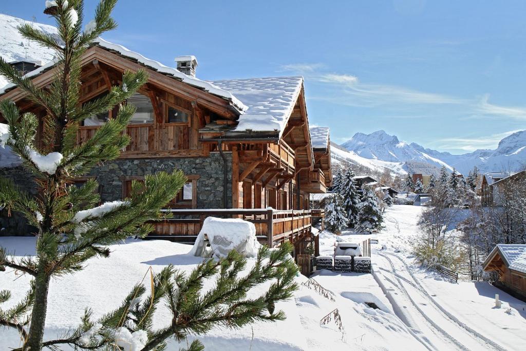 a log cabin in the snow with a tree at Odalys Chalet Le Lys in Les Deux Alpes