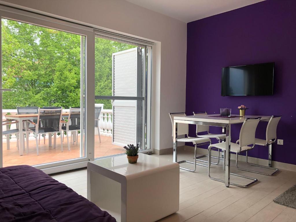 a bedroom with purple walls and a dining room with a table at Apartments Don in Vantačići