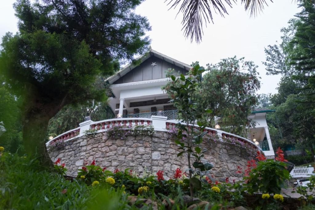 a house behind a stone wall with flowers at Chithirapuram Palace in Munnar