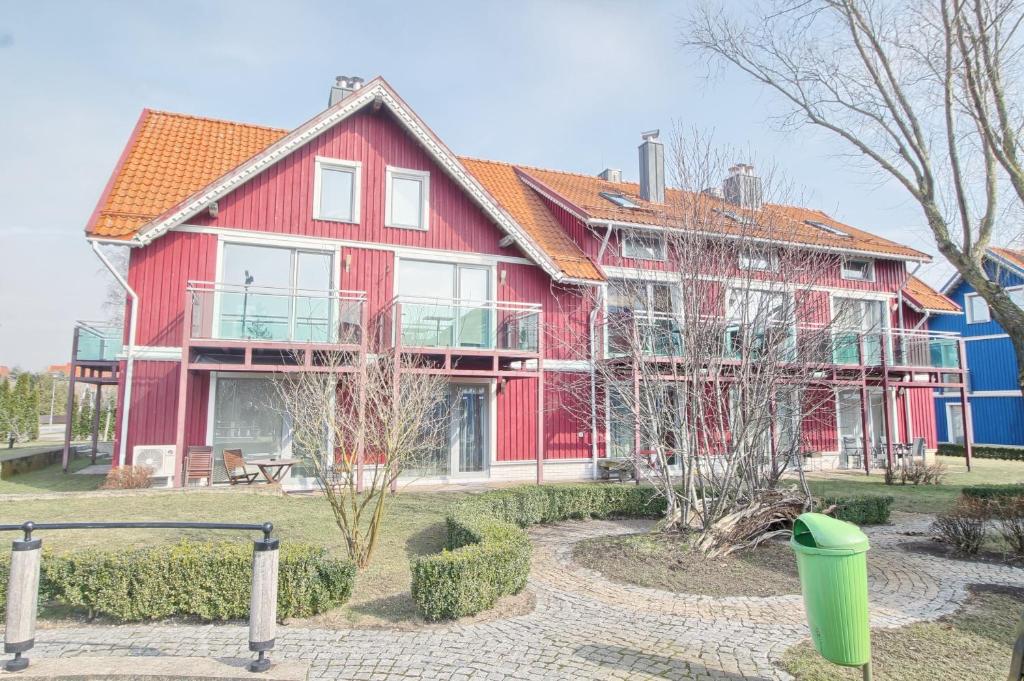 een groot rood huis met een groene vuilnisbak ervoor bij Townhouse near the Curonian Lagoon in Pervalka