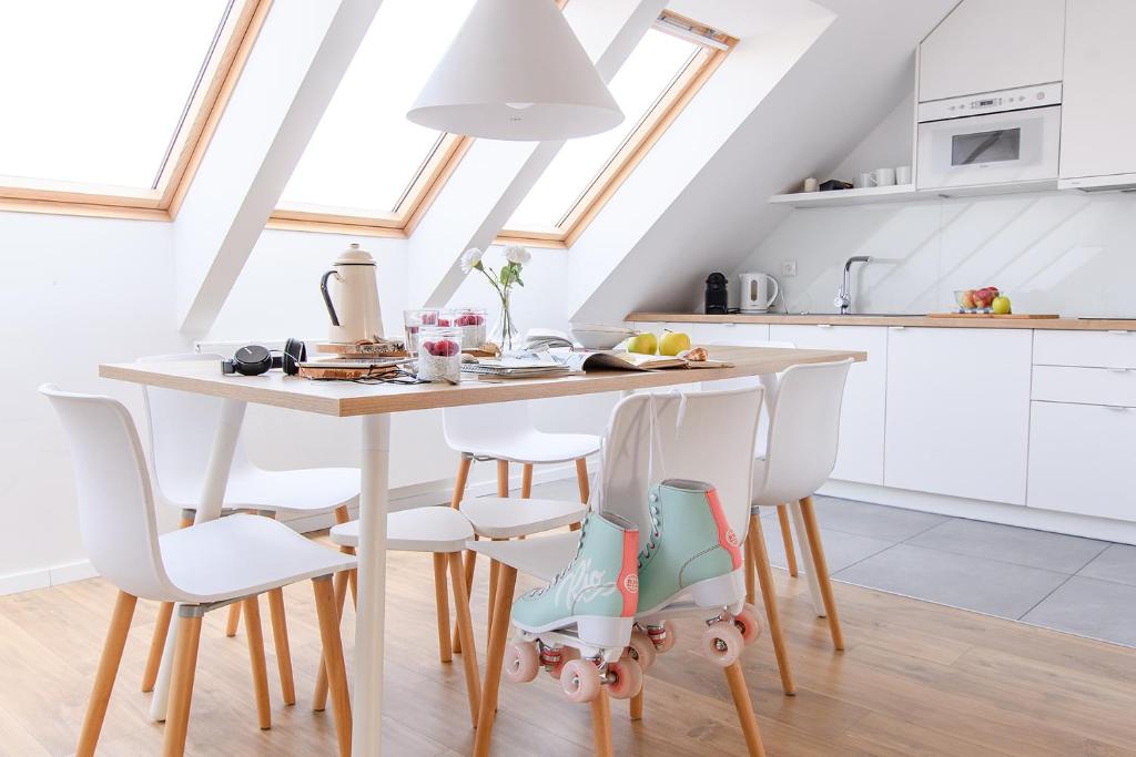 a white kitchen with a wooden table and chairs at Apartamenty Nadmorskie in Kołobrzeg