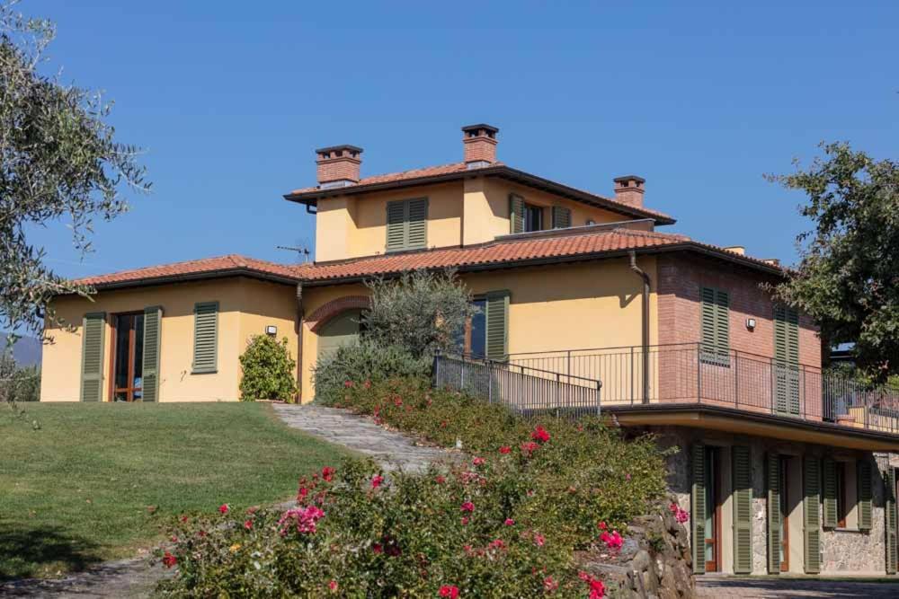 ein großes gelbes Haus mit einem Hof mit Blumen in der Unterkunft Podere Saranna in Pescia