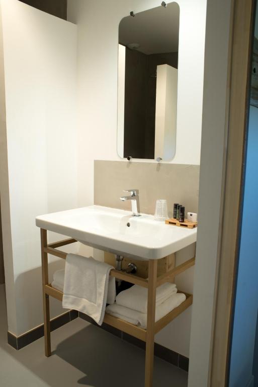 a bathroom with a white sink and a mirror at Hôtel Le 23 in Sauternes